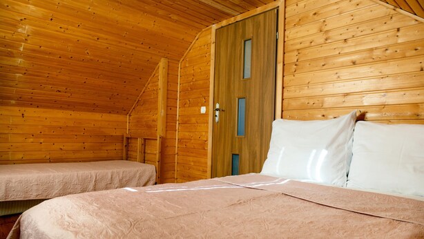 Eine Holzhütte mit zwei Betten und geneigter Decke.