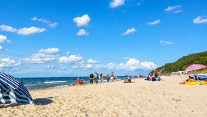 Ein Strand mit Menschen, Sonnenschirmen und blauem Himmel.