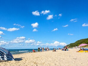 Ein Strand mit Menschen, Sonnenschirmen und blauem Himmel.