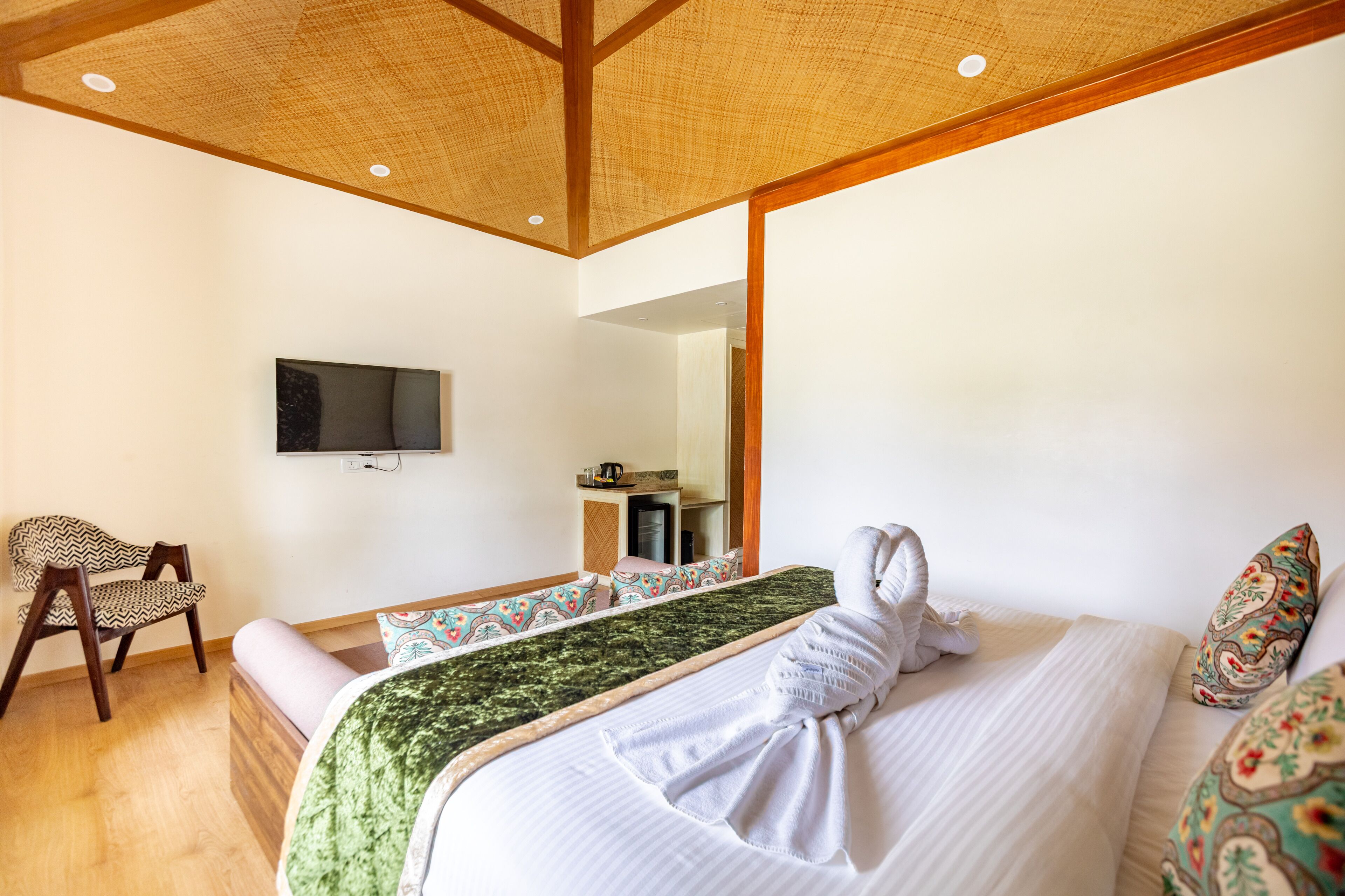 A hotel room with a bed, a chair, a television, and a kitchenette.