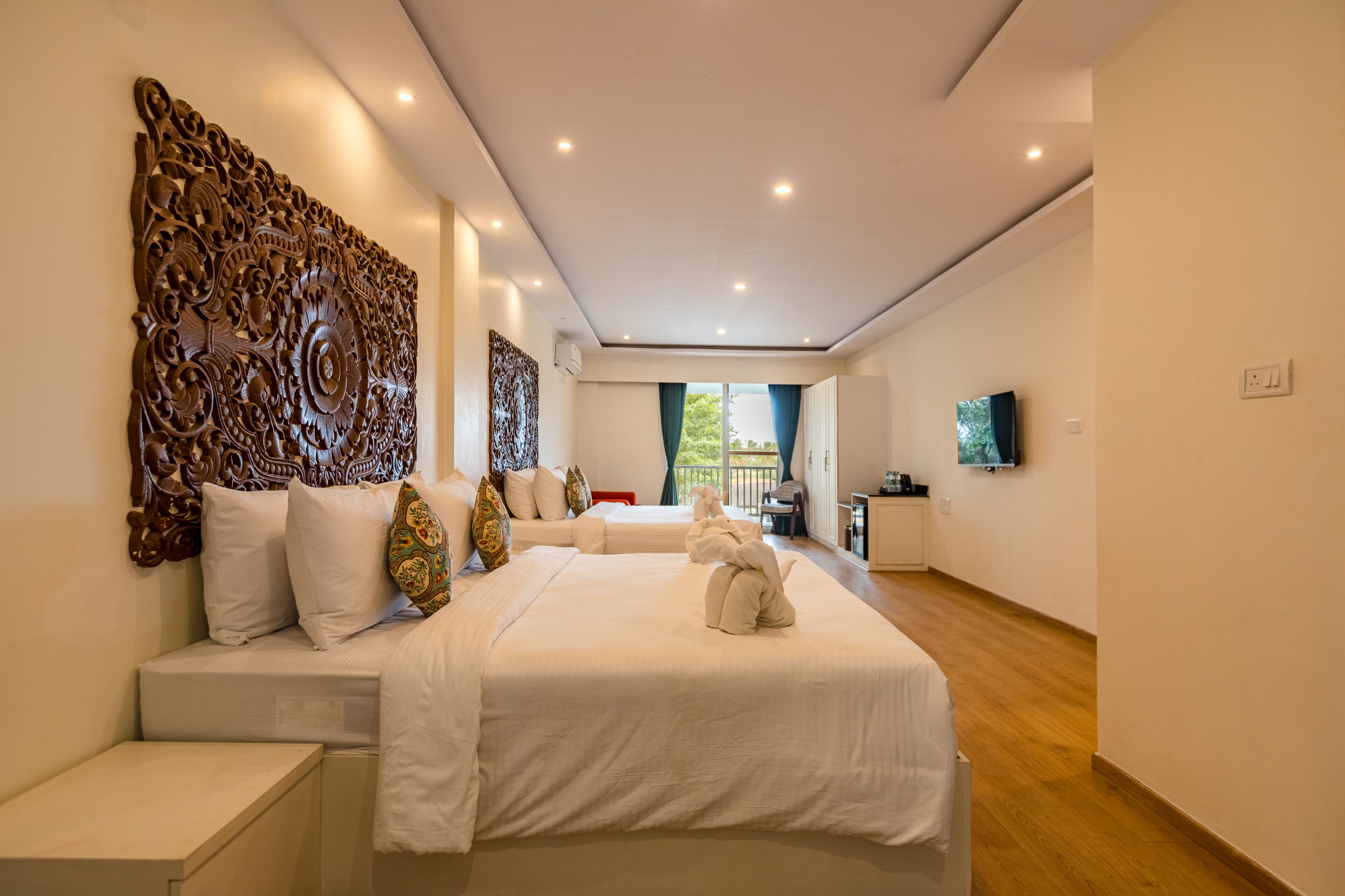 Habitación de hotel moderna con una cama grande, cabecera de madera, televisor de pantalla plana y vistas al exterior.