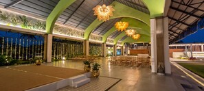 Un espacio interior con asientos escalonados, iluminación decorativa y techo verde.