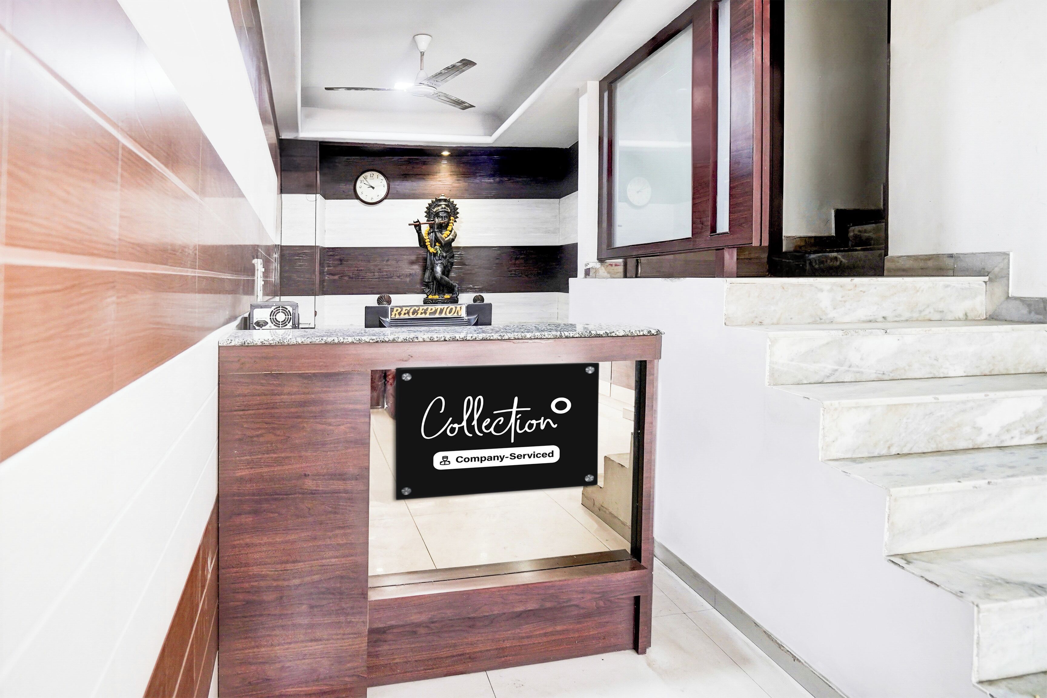 A reception area with a wooden counter, a clock, and a statue.
