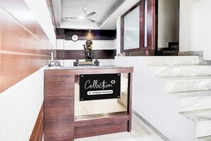 A reception area with a wooden counter, a clock, and a statue.