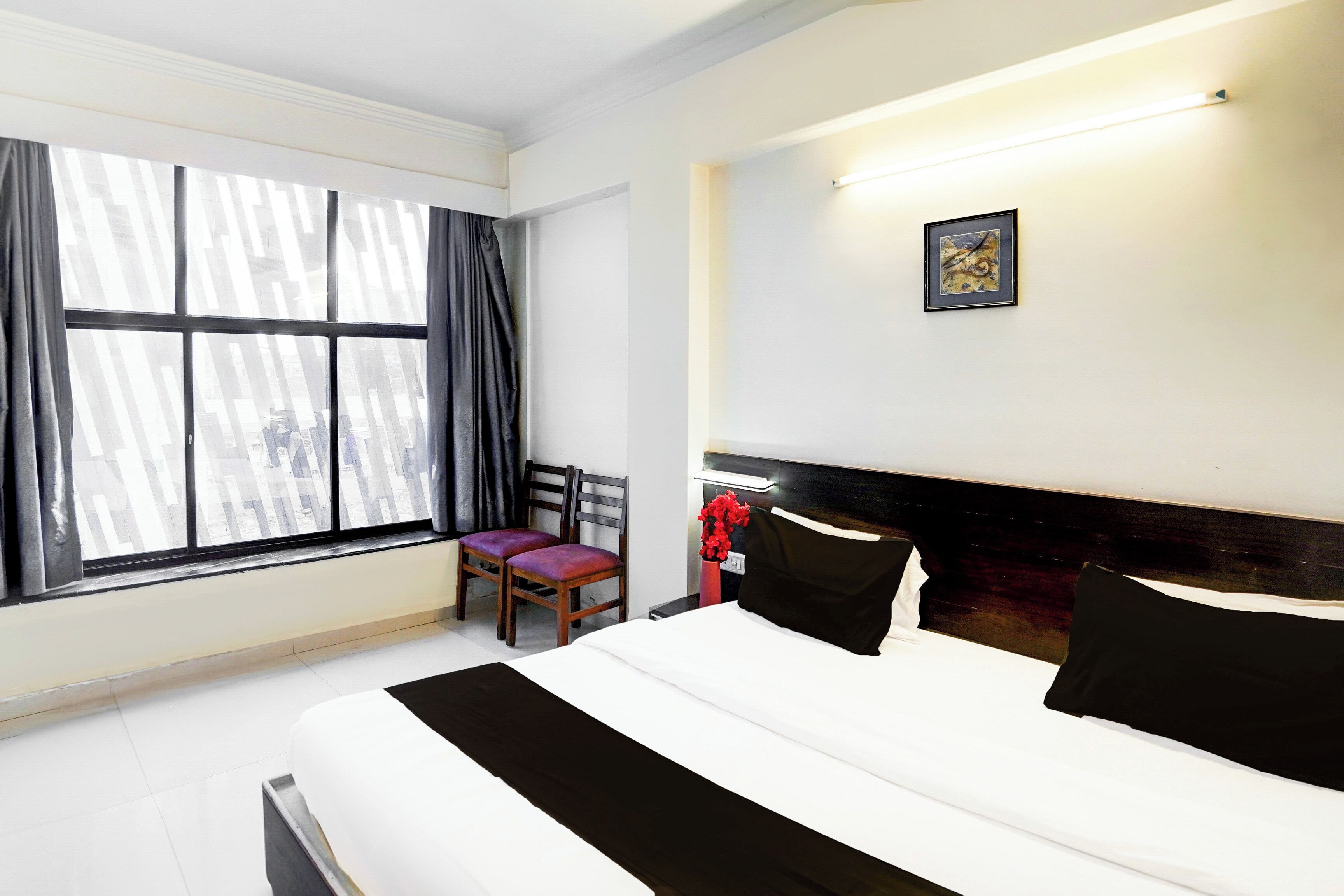 Une chambre d’hôtel avec un grand lit, une chaise, un bureau et une fenêtre avec des rideaux.
