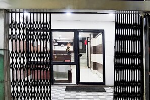 A hotel entrance with a metal gate, a reception desk, and a fire extinguisher.