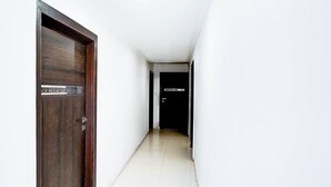 Un pasillo con una puerta de madera a la izquierda y una puerta negra con un letrero a la derecha.