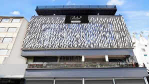 Un edificio con letrero de la empresa, techo inclinado y entrada portonada.