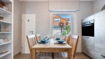 A compact kitchen with a built-in oven and a dining area with a wooden table set for two.