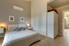 Ein Schlafzimmer mit Bett, Nachttischen, einem Kleiderschrank und einer Klimaanlage.