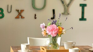 Et træbord med en hvid vase med blomster, to hvide kopper og en træbakke.