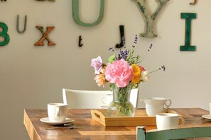 Ein Holztisch mit einer weißen Vase mit Blumen, zwei weißen Tassen und einem Holztablett.