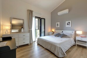 Ein Schlafzimmer mit Bett, Nachttischen, einem Schminktisch und einem Spiegel, sowie einer Klimaanlage.