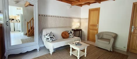 Una sala de estar con sofá, una mesita, una silla y techo de madera.