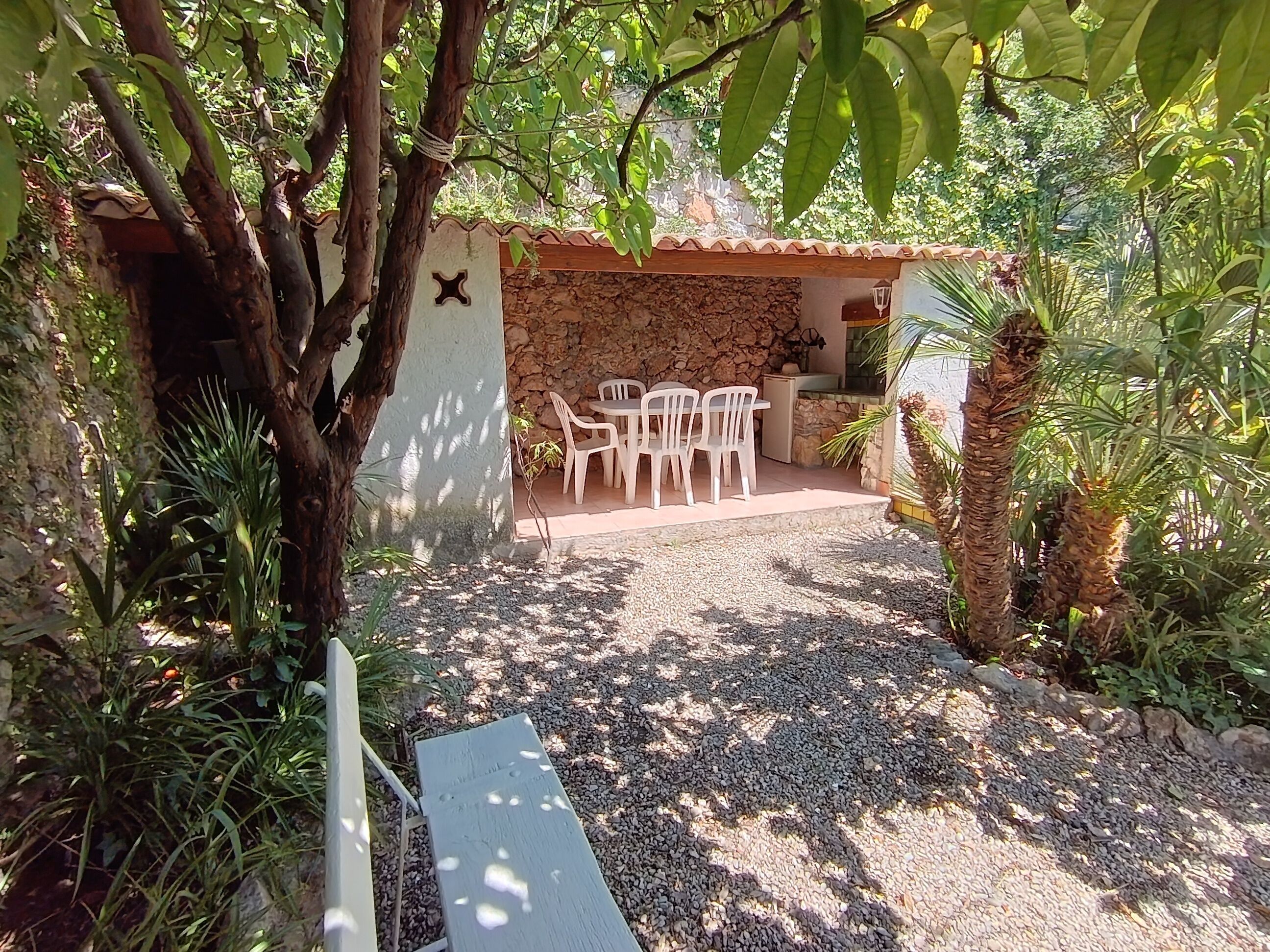 A patio area with a stone wall, a table, and chairs.