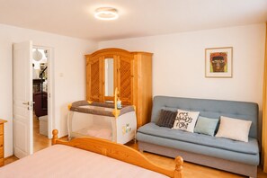 A bedroom with a bed, a wooden wardrobe, a sofa, and a crib. - Mrzezyno Holiday Home, for 4 People (Trzebiatow)