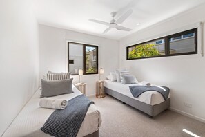A bedroom with two beds, a ceiling fan, and large windows. - Luxury Retreat - Villa 17 on Hastings St (Noosa Heads)