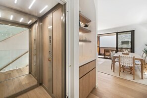 A modern interior with a wooden staircase, a dining area with a table and chairs, and a view of the outdoors through a glass door. - Luxury Retreat - Villa 17 on Hastings St (Noosa Heads)