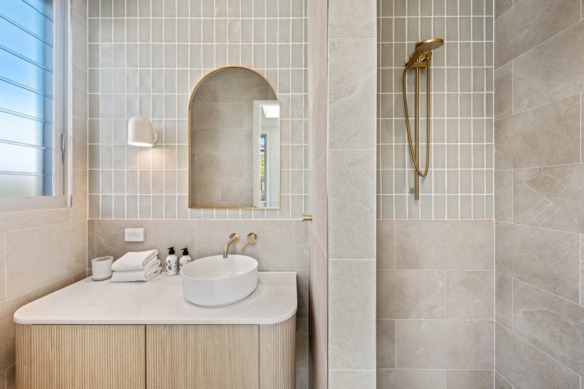Un bagno moderno con un mobile lavabo, uno specchio e una doccia.