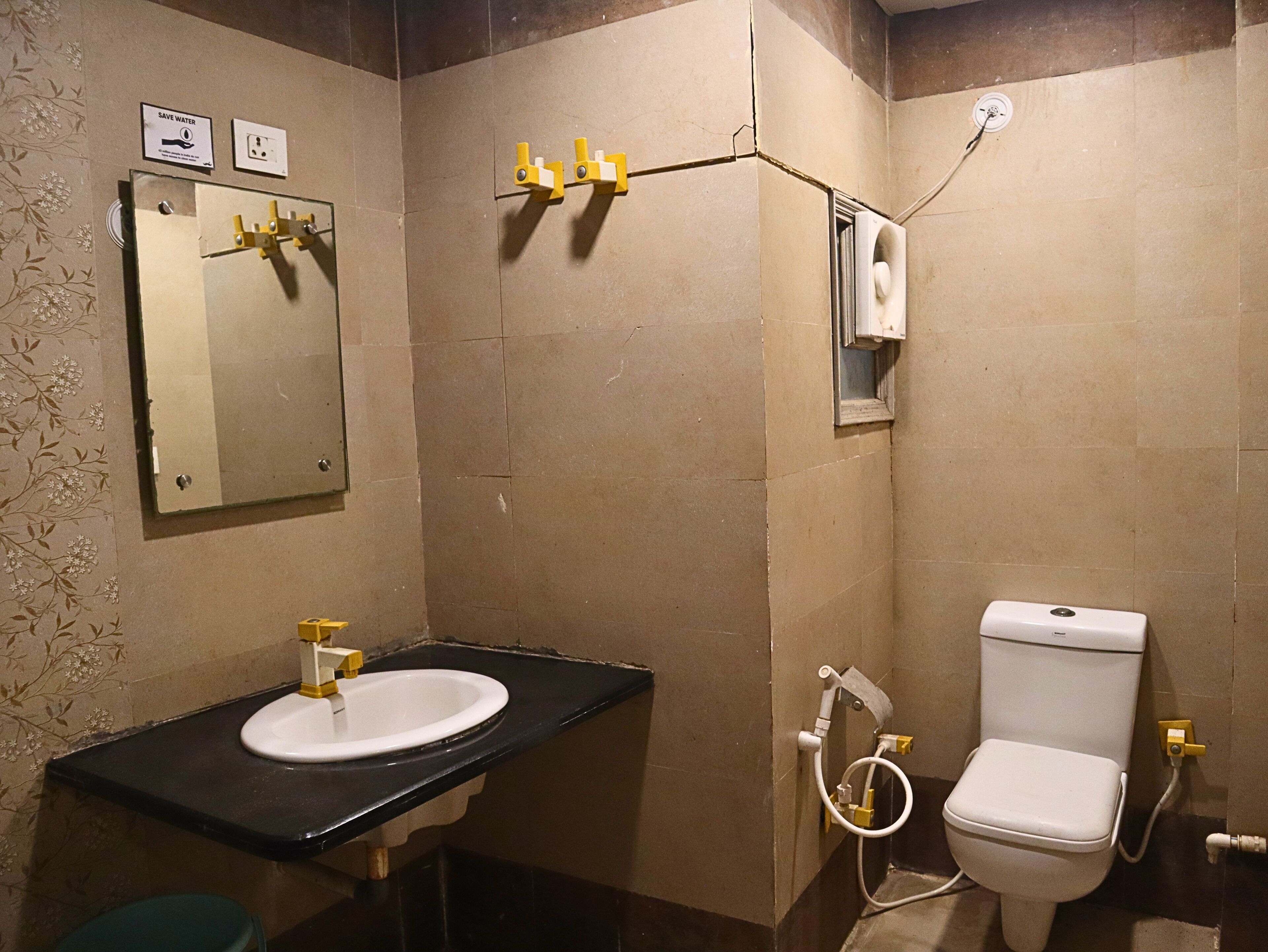 Et badeværelse med vask, spejl, toilet og håndklædestang.