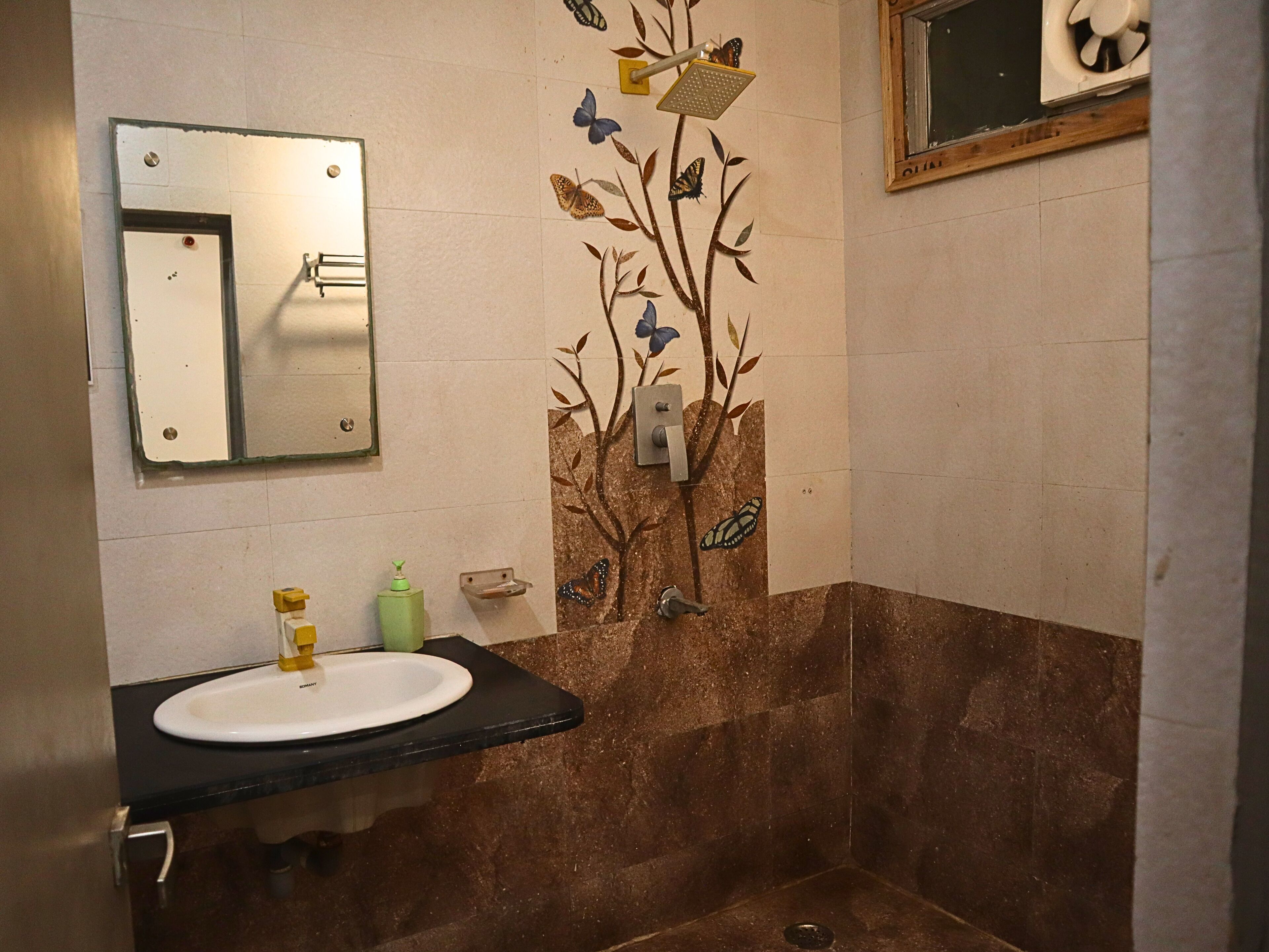 Casa de banho com lavatório, espelho, chuveiro e decoração de parede.