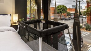 Een hotelkamer met een bed, een raam met uitzicht op de straat, en een bijzonder raamontwerp.