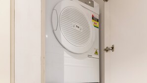Een gestapelde wasmachine en droger met zichtbare merktekens en energielabels voor energie- en waterverbruik.