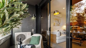 Een modern interieur met een zithoek, een tafel met fles en glas, en een groot raam met uitzicht op groen.