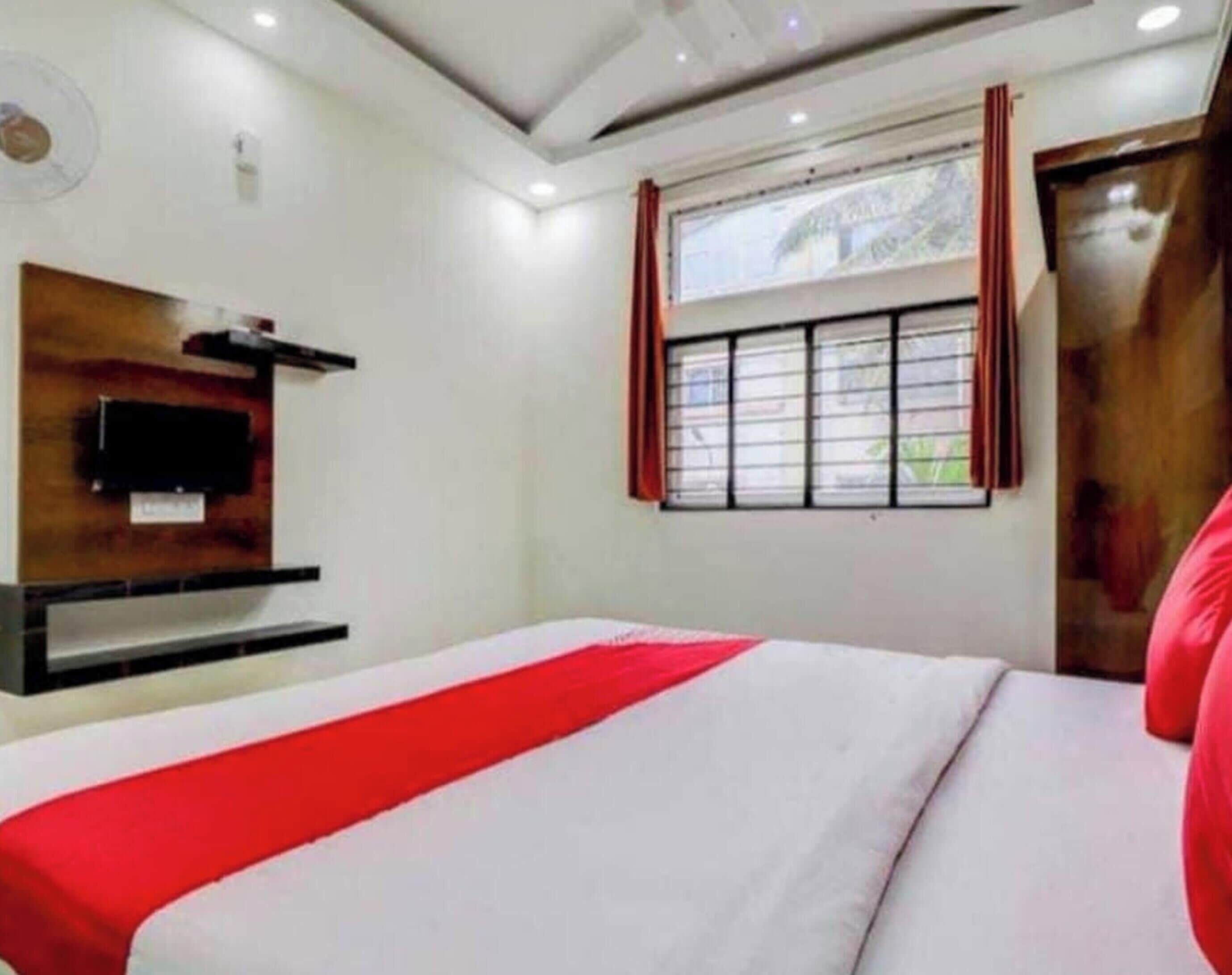 A hotel room with a bed, a TV mounted on the wall, and a window with curtains.