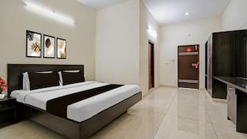 Een hotelkamer met een bed, nachtkastje en een aan de muur bevestigde televisie.