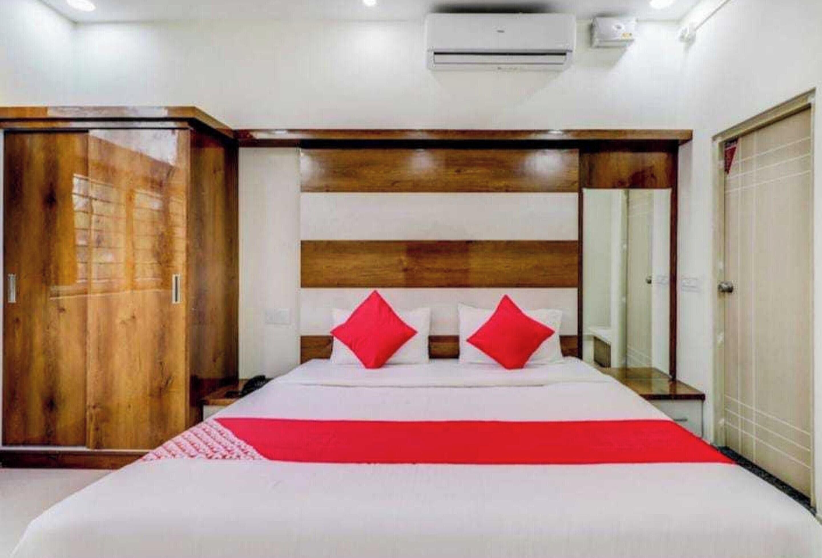 A hotel room with a large bed, a wooden headboard, a wardrobe, and a mirror.