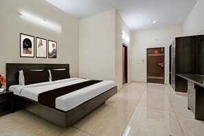 Habitación de hotel con cama, escritorio, armario y puerta con letrero de 'No Fumar'.