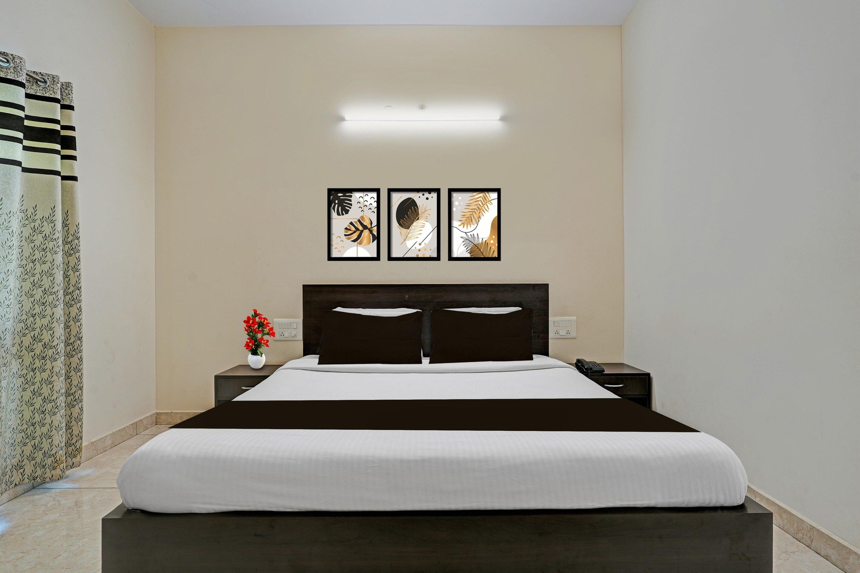 Une chambre d’hôtel avec un lit, une table de chevet, un téléphone et une lampe fixée au mur.