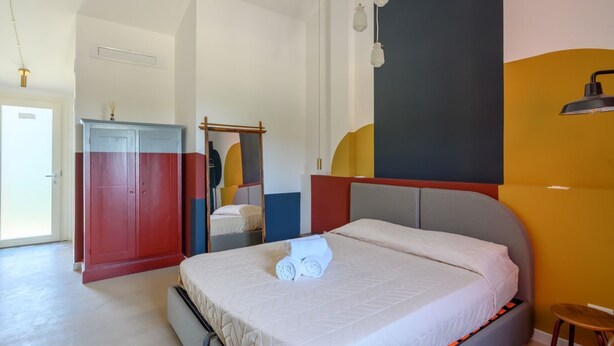 Ein Hotelzimmer mit einem Bett, einem Kleiderschrank, einem Spiegel und einer Wand mit geometrischem Muster.