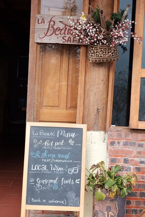 A chalkboard menu outside a wooden door with a sign above it that reads 'La Beaute Menu.'