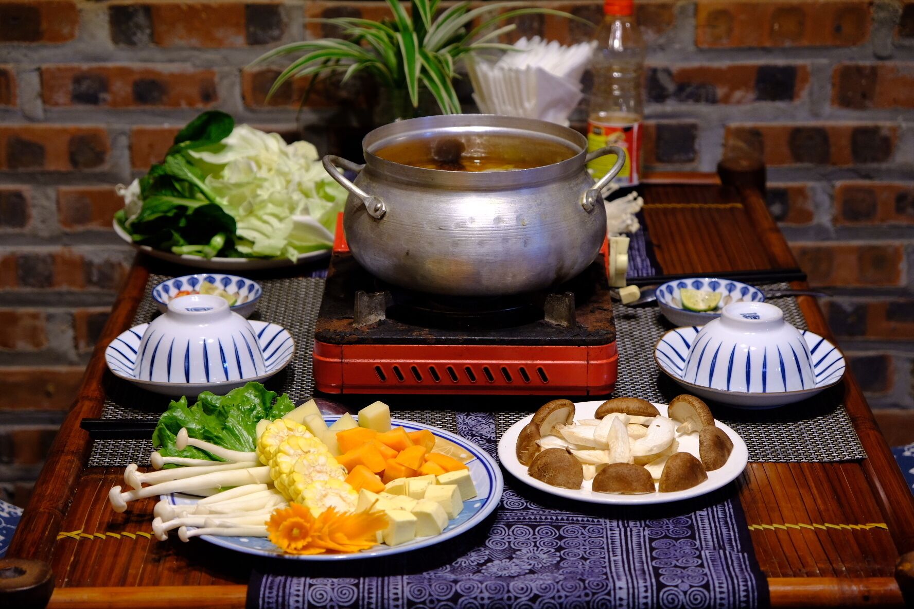 Una mesa dispuesta con diversos platos, entre ellos una olla de sopa, verduras y un plato de champiñones.