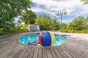 A wooden deck surrounding a swimming pool with a slide, a beach ball, and a small shed. - "Landlust" Vacation Rental in Husum-Schauendahl for up to 4 people (Husum-Schauendahl)