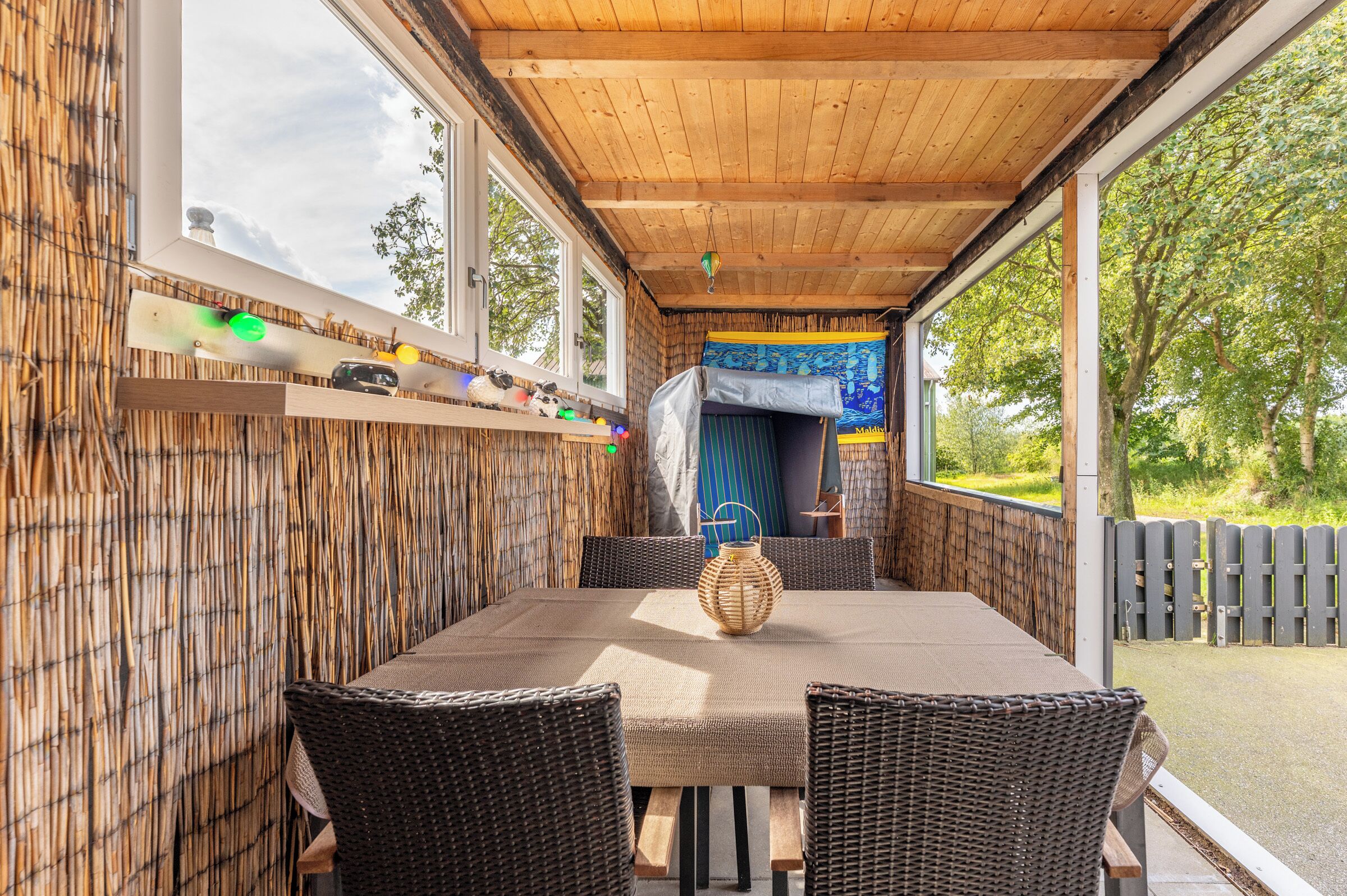 Un espace extérieur abrité, aménagé avec une table, des chaises et une lanterne décorative.