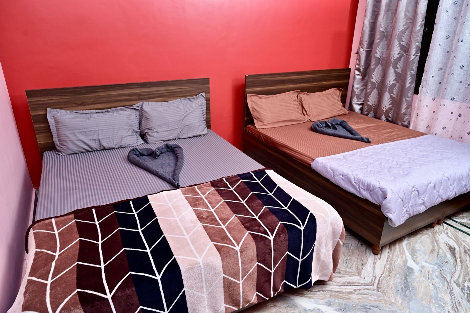 Zwei Betten mit unterschiedlicher Bettwäsche, ein herzförmiges Kopfkissen und eine gemusterte Decke.