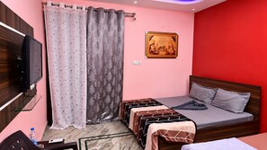 A bedroom with a bed, a television, a water bottle, and a framed picture on the wall. - S4 Homestay  (Amritsar)