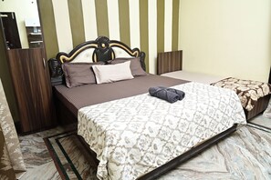 A bed with a patterned bedspread, a headboard, and pillows.