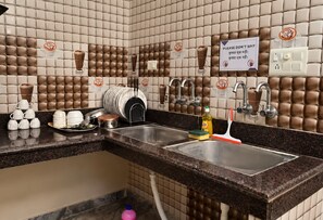 A kitchen area with a sink, a coffee machine, and a sign instructing not to spit. - S4 Homestay (Amritsar)