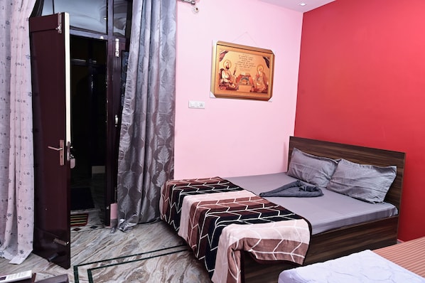 A bedroom with a bed, two bedside tables, a wardrobe, a curtain, and a wall-mounted picture.