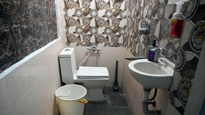 A small bathroom with a toilet, bidet, sink, and a trash bin.