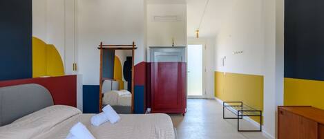 A hotel room with a bed, a wardrobe, a desk, and a chair.