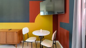 A room with a flat-screen TV mounted on the wall, a wooden cabinet, and two round tables with chairs. - GuestHost - Kidane Room 4 Padova (Padua)