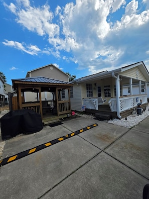 A residential property with a covered porch, a detached garage, and a small outdoor seating area. - Beach Breeze Bungalow | Outdoor Oasis | 2BR/2BA (Myrtle Beach)