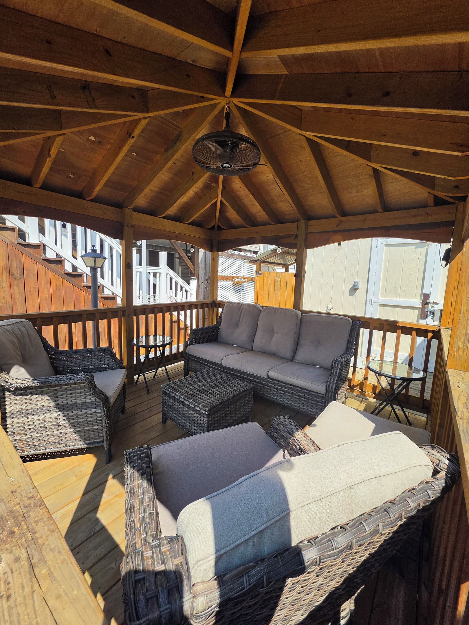 A covered outdoor seating area with wicker furniture and a ceiling fan.