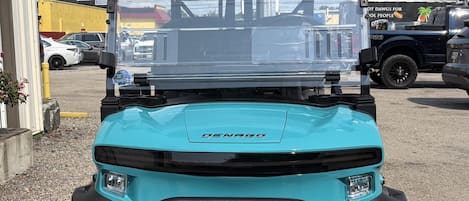 A blue utility vehicle with a roof, large tires, and a front grille.