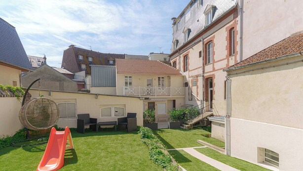 A residential courtyard with a red slide, outdoor seating, and a well-maintained lawn. - 1bdr/3p Flat - Balcony - in the Heart of Deauville (Deauville)